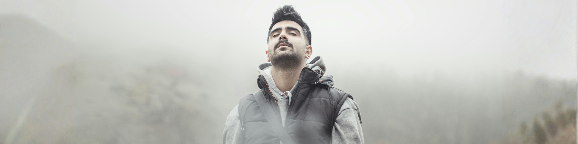 Mann steht mit geschlossenen Augen in ruhiger Umgebung – Symbol für Selbstreflexion, Wachstum und persönliche Entwicklung.