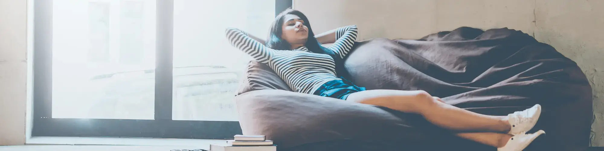 Frau liegt entspannt auf einem Sofa und atmet tief durch – Sinnbild für Entlastung, Gelassenheit und Stressabbau.